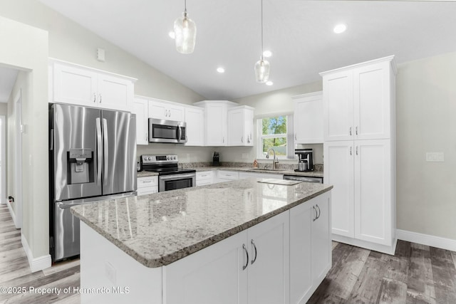 kitchen with lofted ceiling, a kitchen island, stainless steel appliances, white cabinetry, and a sink