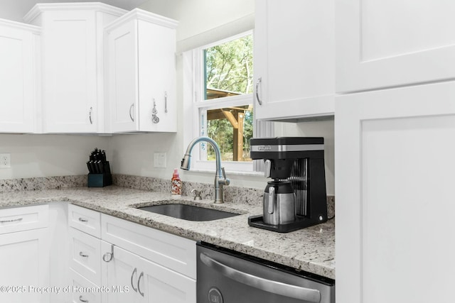 kitchen featuring dishwasher, a sink, light stone countertops, and white cabinets