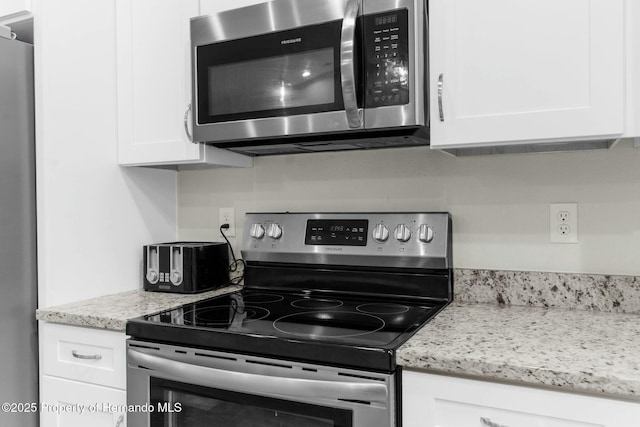 kitchen featuring appliances with stainless steel finishes, white cabinets, and light stone countertops