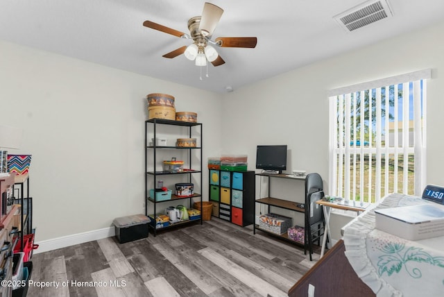 interior space with baseboards, wood finished floors, visible vents, and a ceiling fan