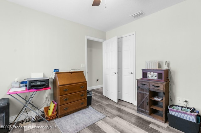 interior space with baseboards, wood finished floors, visible vents, and a ceiling fan