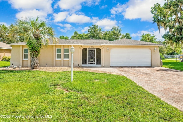 ranch-style house featuring a front lawn, decorative driveway, a garage, and stucco siding