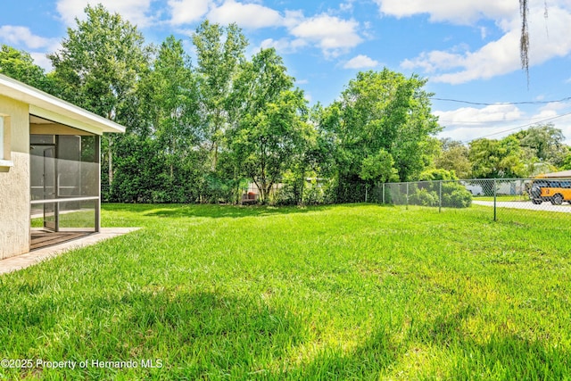 view of yard featuring fence and a sunroom