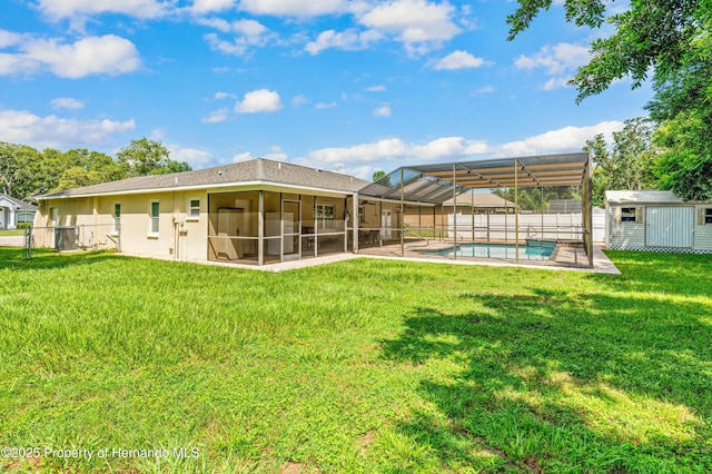 rear view of property featuring an outbuilding, a fenced in pool, a shed, a fenced backyard, and a lawn