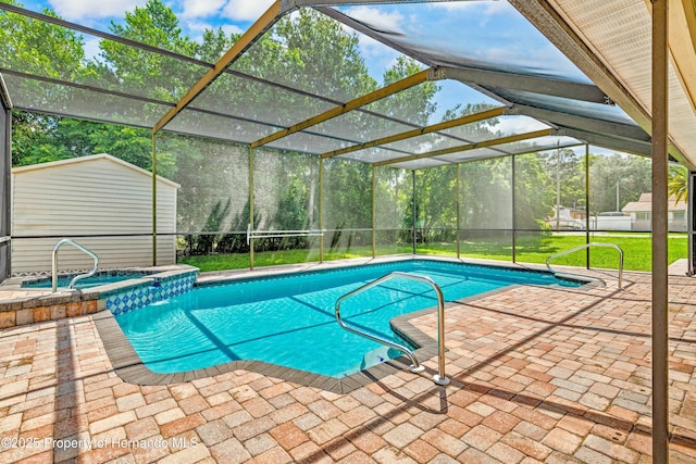 view of pool with glass enclosure, an outbuilding, a pool with connected hot tub, a patio area, and a lawn