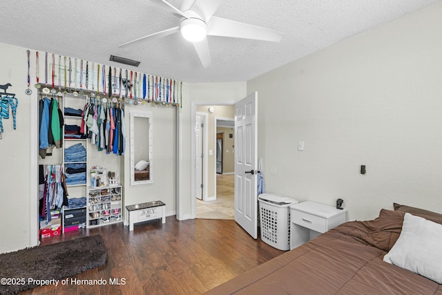 bedroom with visible vents, wood finished floors, a closet, a textured ceiling, and a ceiling fan