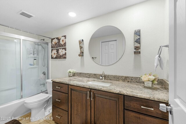 bathroom featuring visible vents, toilet, combined bath / shower with glass door, and vanity