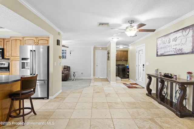 kitchen featuring visible vents, ornamental molding, a ceiling fan, dark countertops, and appliances with stainless steel finishes