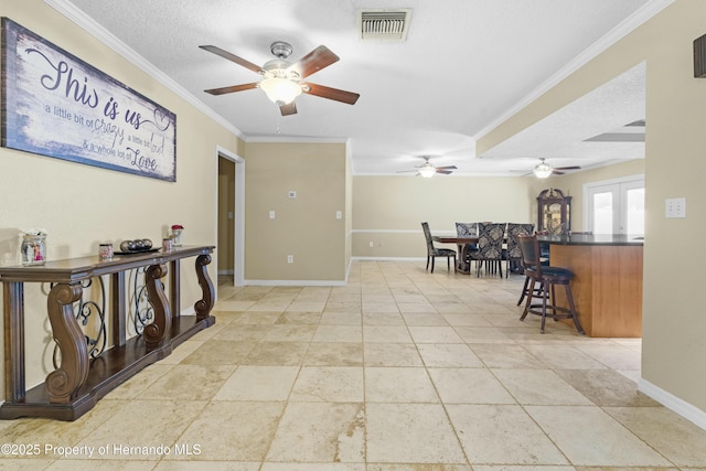 interior space with visible vents, crown molding, baseboards, french doors, and a textured ceiling