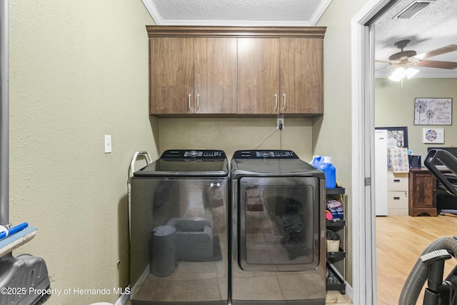 laundry room featuring visible vents, washing machine and clothes dryer, cabinet space, a textured ceiling, and crown molding