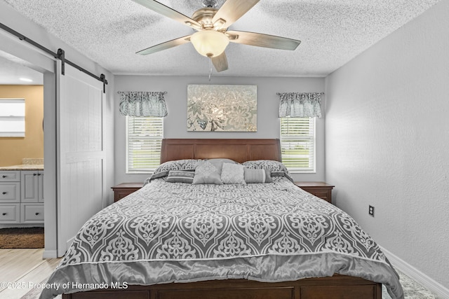 bedroom featuring multiple windows, a textured ceiling, a barn door, and a textured wall