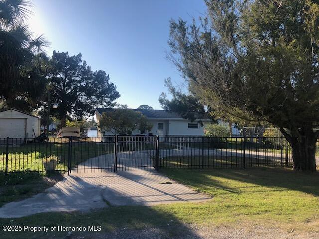 view of property hidden behind natural elements with a front lawn, a gate, and fence