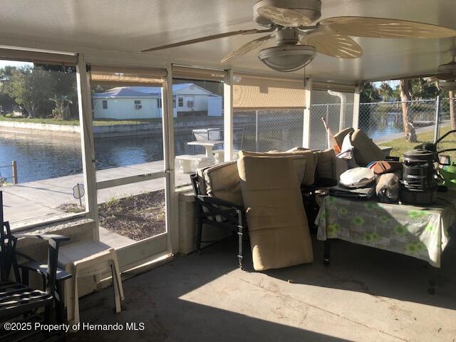 sunroom / solarium with a water view and a ceiling fan