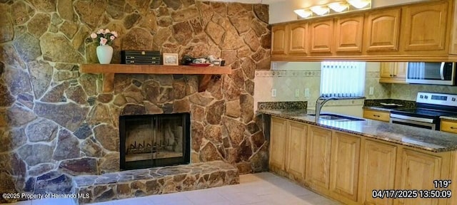12437 Drayton Dr, Spring Hill, FL 34609 - kitchen featuring stainless steel appliances, a stone fireplace, a sink, and dark stone counters
