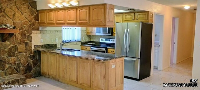 12437 Drayton Dr, Spring Hill, FL 34609 - kitchen featuring stainless steel appliances, a peninsula, a sink, dark stone counters, and light tile patterned floors
