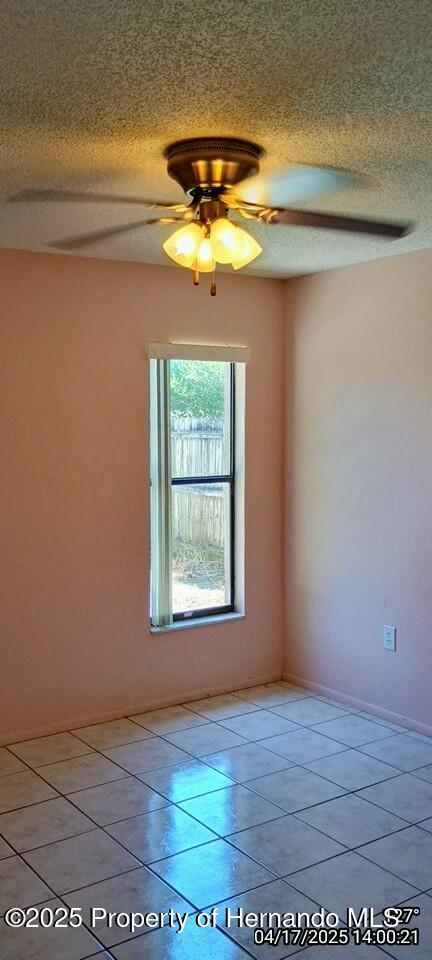 12437 Drayton Dr, Spring Hill, FL 34609 - spare room with a ceiling fan, a textured ceiling, and light tile patterned floors
