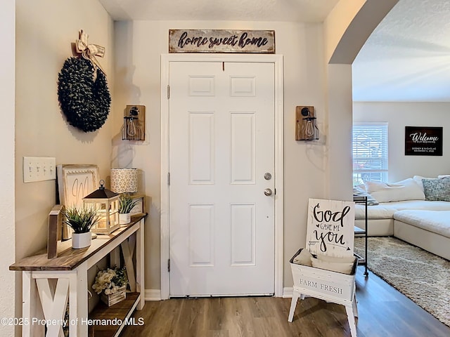 entryway featuring arched walkways and wood finished floors