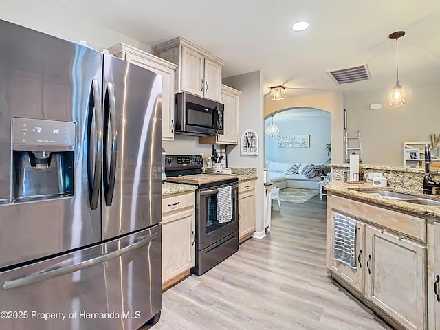 kitchen with visible vents, light wood-type flooring, a sink, arched walkways, and appliances with stainless steel finishes