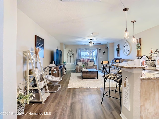 living room with visible vents, dark wood-type flooring, baseboards, a textured ceiling, and a ceiling fan