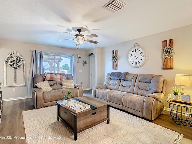 living room with arched walkways, visible vents, ceiling fan, and wood finished floors