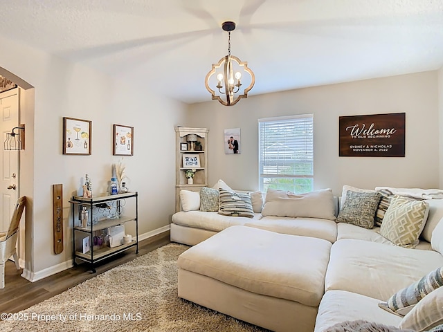 living room featuring a chandelier, baseboards, and wood finished floors