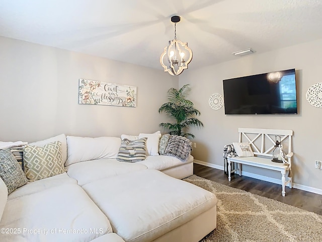 living area with baseboards, an inviting chandelier, and wood finished floors