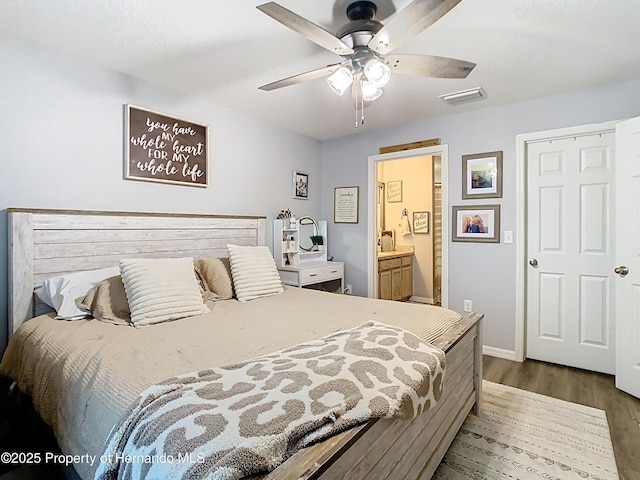 bedroom featuring a ceiling fan, baseboards, wood finished floors, visible vents, and connected bathroom