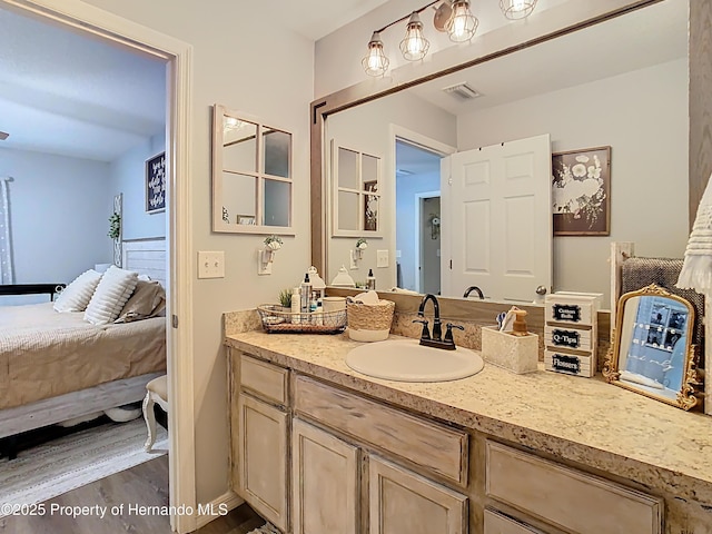 bathroom featuring vanity, wood finished floors, visible vents, and ensuite bathroom