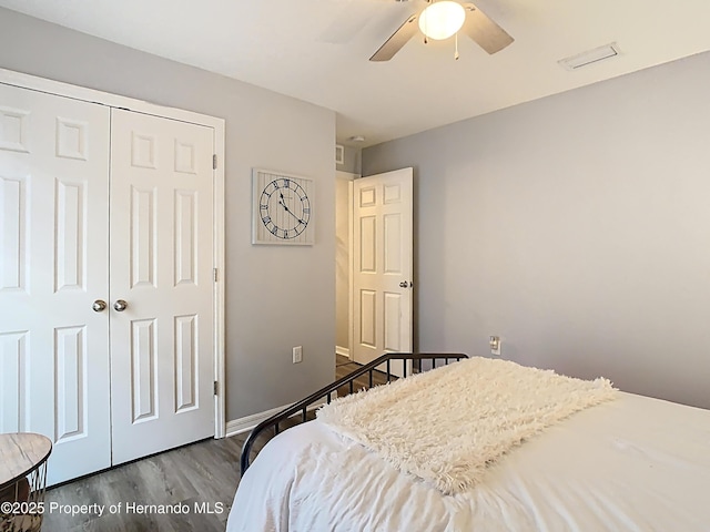 bedroom with a closet, baseboards, wood finished floors, and a ceiling fan