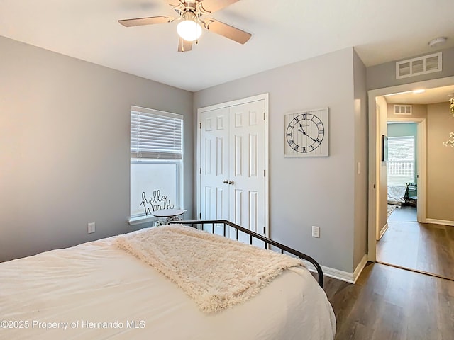 bedroom featuring wood finished floors, visible vents, a closet, and baseboards