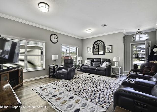 living area featuring visible vents, crown molding, baseboards, wood finished floors, and arched walkways