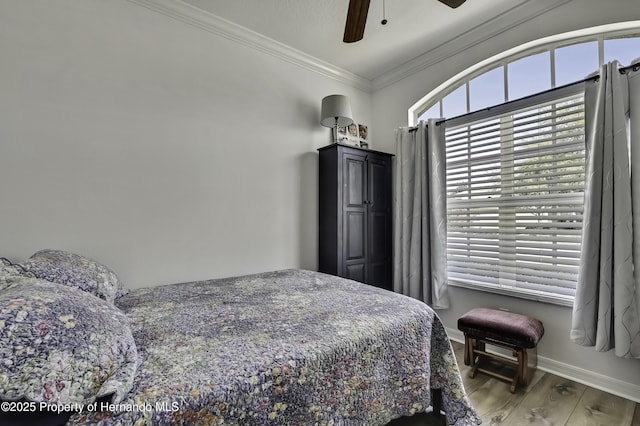 bedroom with baseboards, wood finished floors, ornamental molding, and a ceiling fan