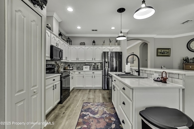 kitchen featuring visible vents, backsplash, ornamental molding, black appliances, and a sink