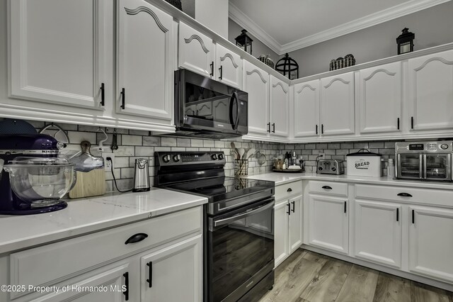 kitchen featuring tasteful backsplash, white cabinetry, black appliances, and ornamental molding