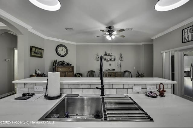 kitchen featuring arched walkways, visible vents, crown molding, and stainless steel fridge with ice dispenser