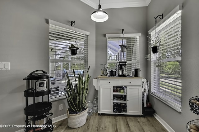 interior space with crown molding, decorative light fixtures, wood finished floors, and baseboards