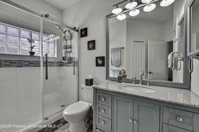 bathroom featuring a shower stall, toilet, and vanity