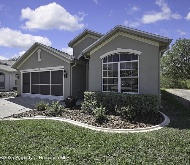 ranch-style house with stucco siding, driveway, a front yard, and a garage