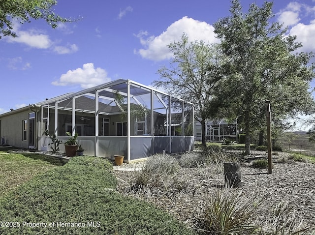 back of property featuring a lanai and a yard