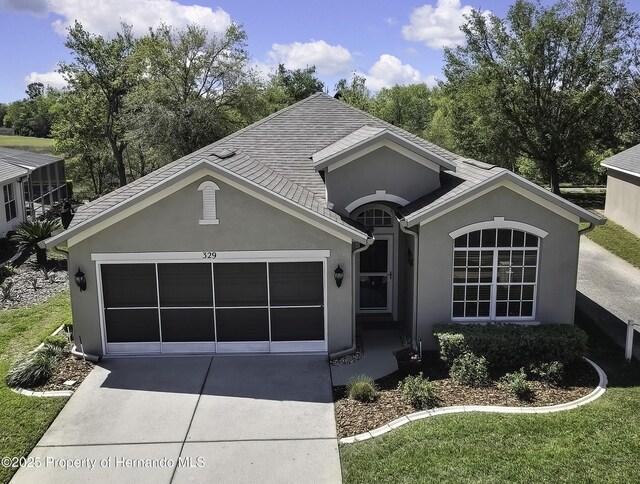 ranch-style house with a shingled roof, an attached garage, driveway, and stucco siding