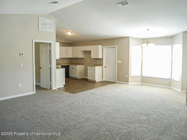 kitchen with an inviting chandelier, white cabinets, carpet flooring, and visible vents