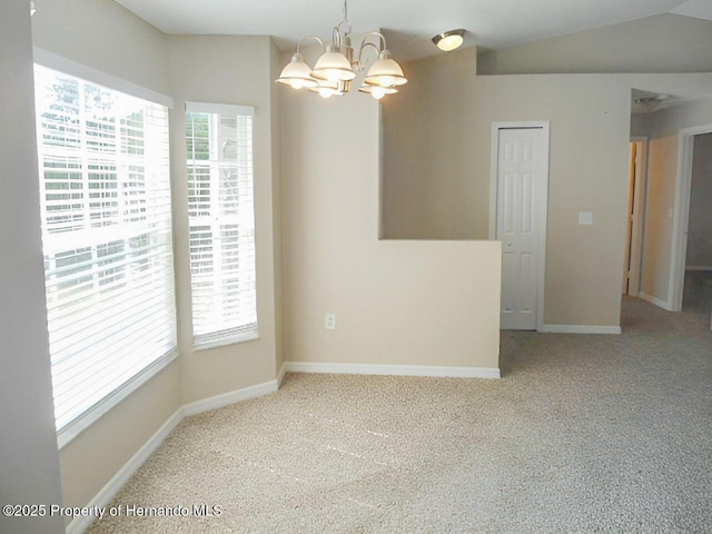 empty room with vaulted ceiling, a notable chandelier, baseboards, and carpet floors