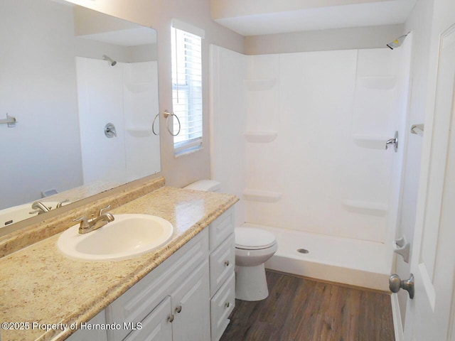 bathroom featuring vanity, toilet, wood finished floors, and a shower