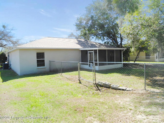 back of house with a lawn, fence, a sunroom, and stucco siding