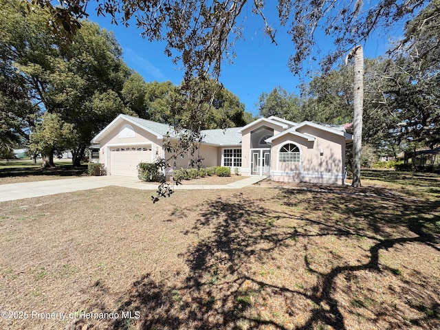 ranch-style house featuring stucco siding, driveway, a front lawn, and a garage