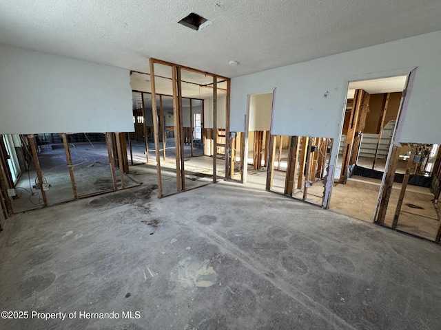 empty room with unfinished concrete floors and a textured ceiling