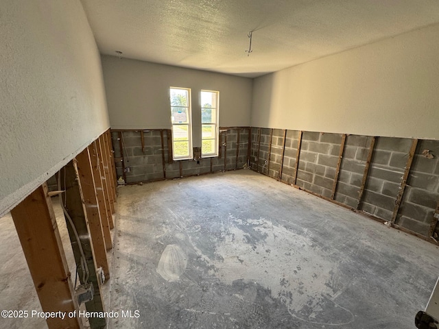 unfurnished room with unfinished concrete flooring and a textured ceiling