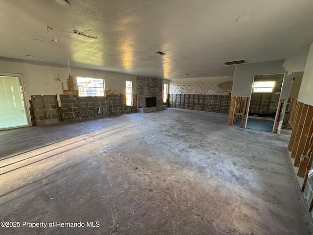 miscellaneous room featuring a fireplace, visible vents, concrete floors, and a textured ceiling