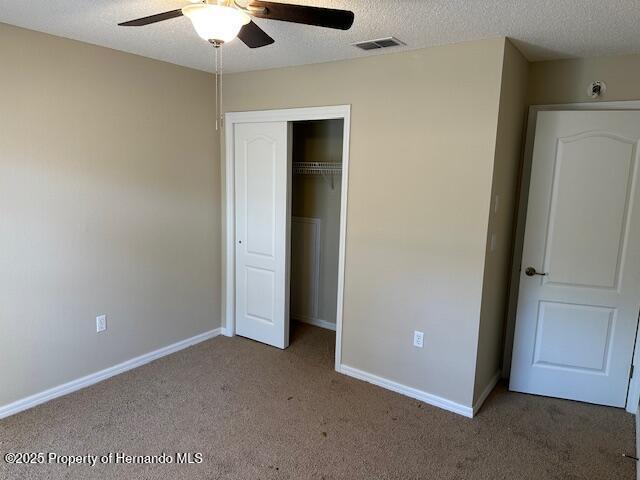 unfurnished bedroom with visible vents, carpet flooring, a textured ceiling, and baseboards