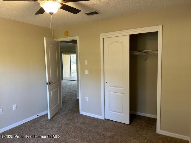 unfurnished bedroom featuring carpet, baseboards, visible vents, a closet, and a textured ceiling